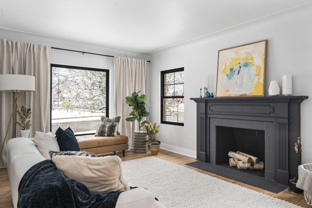 A living room layout with a sofa, window seat, fireplace, and rug.